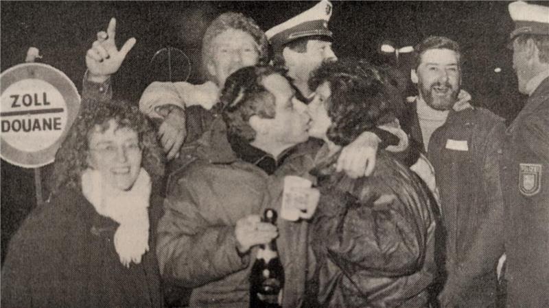 Die GZ schreibt zu diesem Bild 1989/90: „Ein kleines Küsschen zum Jahreswechsel und dann auch noch direkt an der Grenze zur DDR, wer kann da schon widerstehen? Besonders, wenn die ganze Aktion auch noch unter dem Schutz von zwei freundlichen Polizeibeamten steht.“