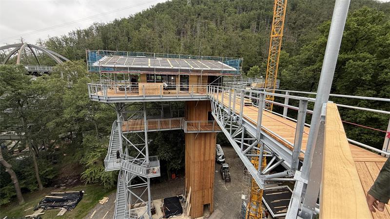 Das Bild zeigt eine hohe Stahl- und Holzkonstruktion, einen Turm, auf dem ein Gebäude steht.