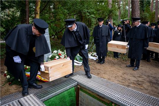 Die Gebeinekisten mit menschlichen Knochen werden nach der Trauerfeier in ein Grab auf dem Waldfriedhof Berlin-Dahlem hinabgelassen.