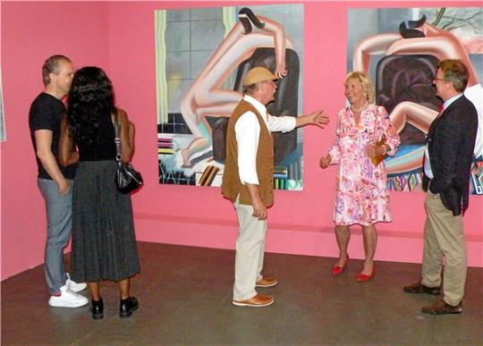 Die Gemälde von Kristina Schuldt (siehe kleines Foto) haben ihre ganz eigene Ästhetik und regen die Besucher der Vernissage (großes Bild) zu lebhaften Diskussionen an.  Fotos: Habel