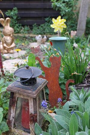 Haustier im eigenen Garten begraben: Was ist erlaubt? Gedenkkerze und eine Katze aus Metall.