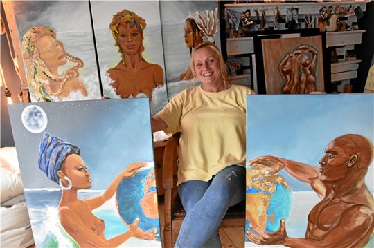 Die Goslarer Künstlerin Tanja Ulrich zwischen ihren Werken. Im Hintergrund ein Triptychon mit Gottheiten, die die Kontinente Amerika, Asien und Afrika verkörpern. Wobei der dunkelhäutige Jüngling im Mittelpunkt, wenn man ihn von ganz links betrachtet, in hellem Gold erstrahlt. Vorn die Gemälde „Tag“ und „Nacht“, die sich auch zu einem Gesamtbild vereinigen lassen. Foto: Petra Hartmann