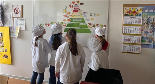Die Grundschüler der Gerhart-Hauptmann-Schule betrachten die Ernährungspyramide der Deutschen Gesellschaft für Ernährung. Anschließend bereiten sie unter anderem Burger zu. Foto: Privat