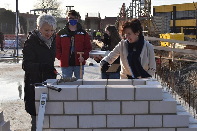 Die HBG-Schüler Antonia Grüll und Jason Holzberg legen mit Landrätin Christiana Steinbrügge (links) und Schulleiterin Katrin Unger (rechts) eine Zeitkapsel in den Grundstein.  Foto: Landkreis