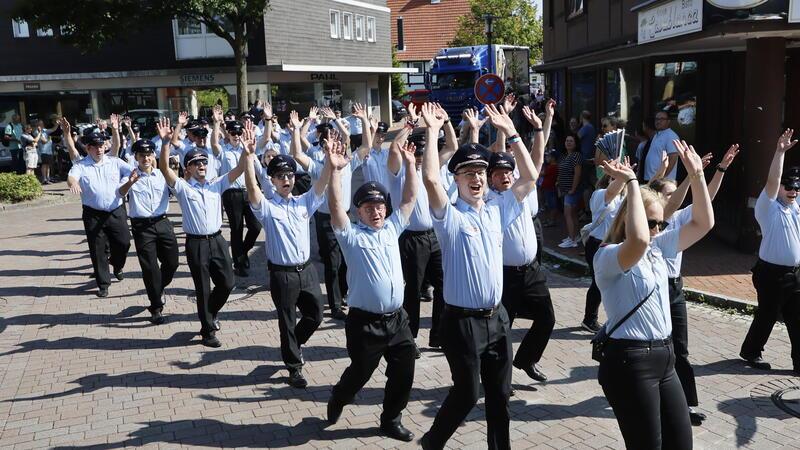 Die Hände zum Himmel: Von dort scheint die Sonne am Sonntag mit Macht, als Langelsheims Feuerwehr durch die Stadt zieht.