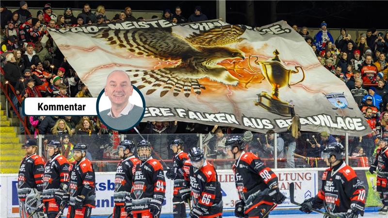 Eishockeyspieler in schwarz-roten Trikots auf dem Eis vor einer Tribüne mit Fans, die ein großes Banner mit einem Falken, einem Pokal und dem Text 'REGIO-MEISTER OHNE FRAGE, UNSERE FALKEN AUS BRAUNLAGE'. halten