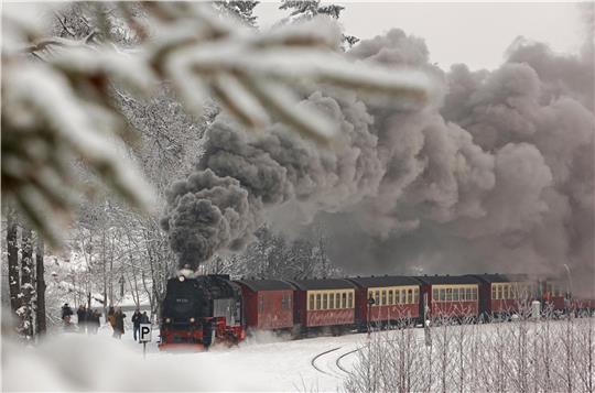 Das Foto zeigt eine Dampflok, die durch den Schnee fährt.