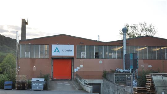 Industriegebäude mit roter Tür und Schild mit Logo und Schriftzug 'JL Goslar'