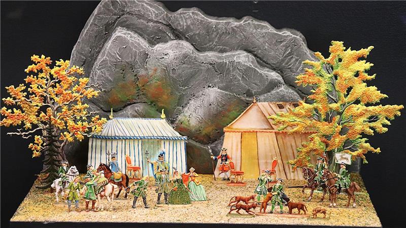 Perücken, Pomp und Pulverdampf im Goslarer Zinnfigurenmuseum Historische Miniaturszene mit mehreren Figuren, Pferden, Hunden, zwei Zelten und zwei herbstlich belaubten Bäumen vor felsigem Hintergrund