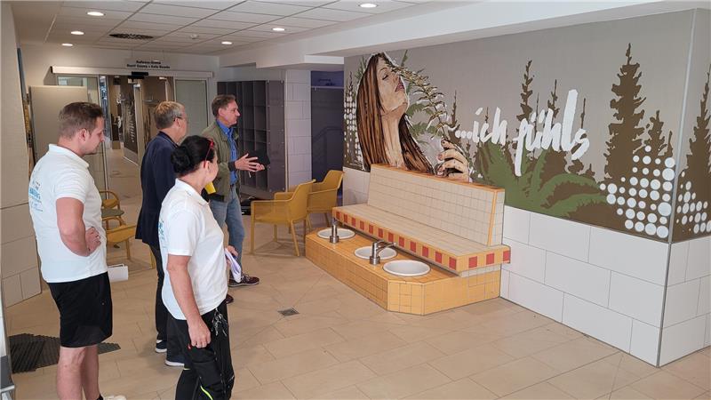Die KTW-Geschäftsführer Christian Klamt und Bernd Vollrodt (von hinten), Schwimmeister Tobias Müller und Thermen-Leiterin Jutta Schmidt begutachten eines der neuen Werke von Grafiker Oliver Schwan, die während der Schließzeit des Schwimmbads entstanden sind.