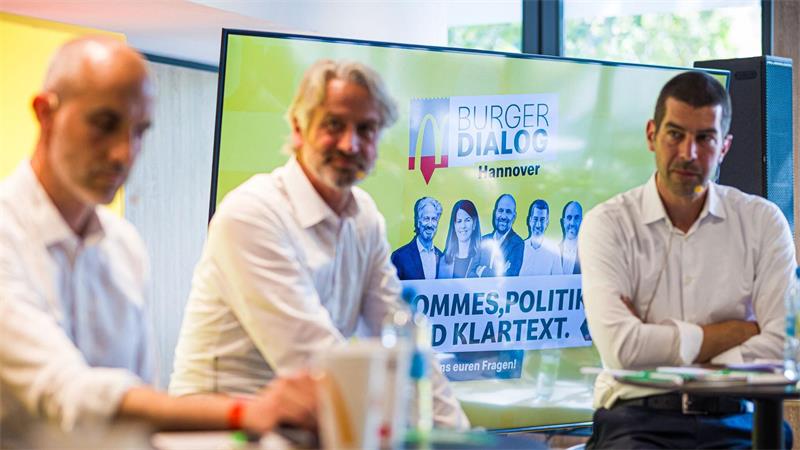 Die Kandidaten für die Oberbürgermeisterwahl 2026 in Hannover, Belit Onay (von links nach rechts, Grüne), Peter Karst (CDU) und Axel von der Ohe (SPD) nehmen am „Burger Dialog Hannover“ in der Filiale einer Fast-Food-Kette teil.