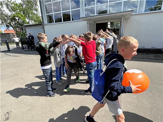 Die Kinder aus den 3. Klassen stehen Spalier für die „Großen“ aus der 4. Klasse und verabschieden den Jahrgang damit aus der Grundschule Harlingerode. Natürlich freuen sich alle, dass nun Ferien sind. Aber ein bisschen Trauer und Wehmut, die Freunde aus der Grundschule zu verlassen, schwingt auch mit. Foto: Schlegel