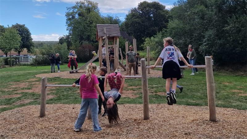 Kinder spielen an einem Klettergerüst aus Holz auf einem Spielplatz im Freien.