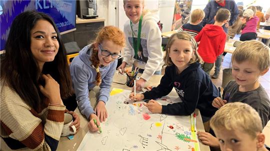 Die Kinder malen zusammen mit Christina Kraus (links) ein Plakat zum Thema Nachhaltigkeit.