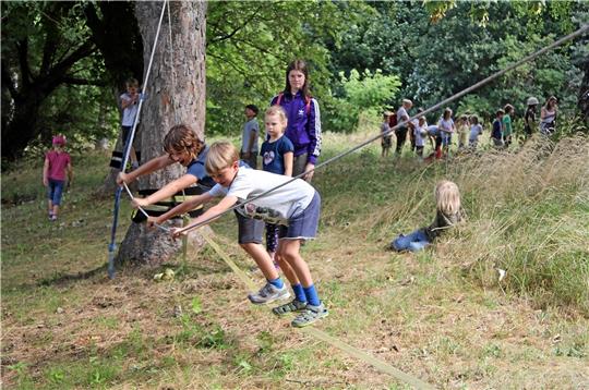 Die Kinder probieren, auf einer Slackline das Gleichgewicht zu halten, was aber gar nicht so leicht ist, auch das Seil zum Festhalten macht es nicht einfacher. Foto: Hohaus