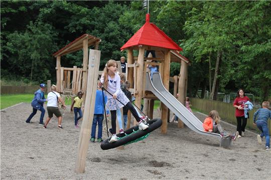 Die Klasse 5a der Grundschule Lautenthal inspiziert den neu eröffneten Spielplatz und freut sich über die Schaukel und Rutsche. Foto: Leifeld