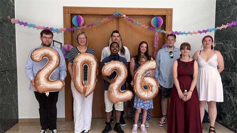 Absolventen aus fünf Klassen feierlich verabschiedet Frauen und Männer stehen nebeneinander, sie halten die Ziffern für 2026 hoch.