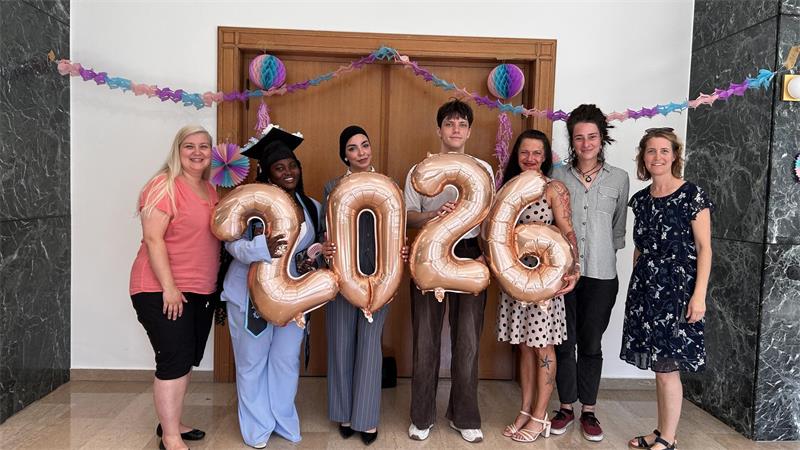 Absolventen aus fünf Klassen feierlich verabschiedet Mehrere Frauen und ein Mann stehen nebeneinander. Sie halten die Ziffern für 2026 in die Höhe.
