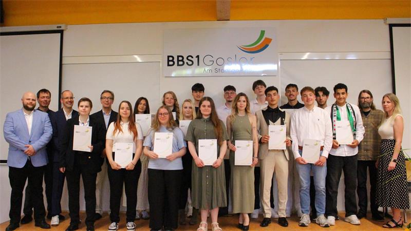 Goslar: 60 Absolventen erreichen die Fachhochschulreife Mehrere Frauen und Männer stehen mit Zeugnissen in der Hand nebeneinander.