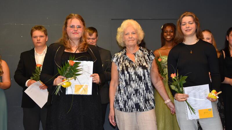 Die Klassenlehrerin Ulrike Wieland beglückwünscht die beiden besten Schülerinnen Yvonne Page (links) und Angelina Adam für die guten Leistungen.