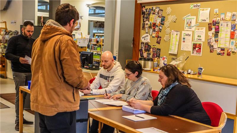 Rätselhafter Zensus: Darum schrumpft der Stadtrat im Oberharz Wahl in der Stadtbibliothek: Drei Wahlhelfer sitzen an Tischen und ein Herr gibt seinen Wahlzettel ab.