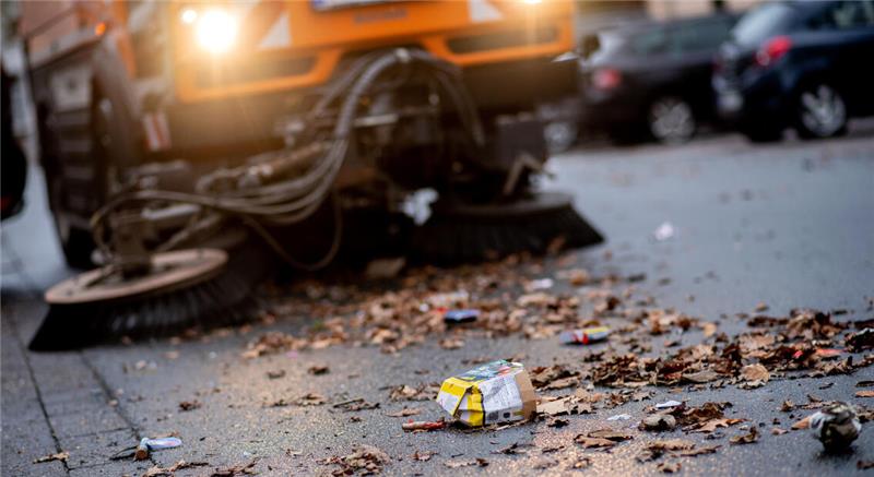 Nahaufnahme einer Straßenkehrmaschine, die Laub und Müll auf einem Gehweg entfernt