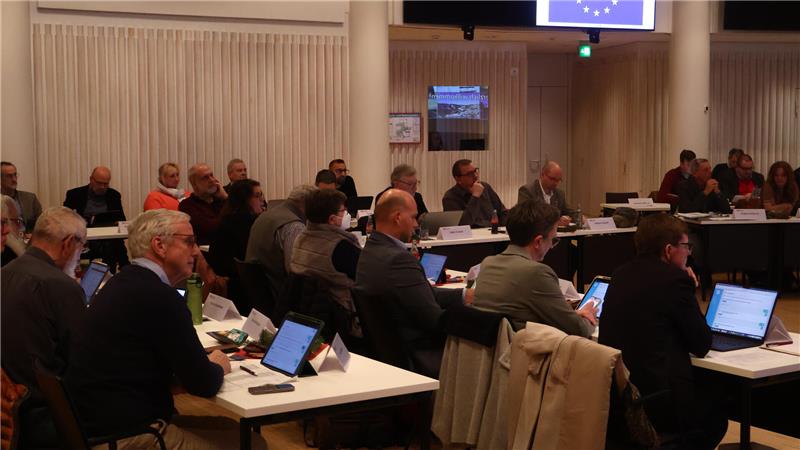 Bis 2029 droht ein Defizit von rund 90 Millionen Euro Blick in die Kreistagssitzung, das Foto zeigt Menschen, die in einem Saal an Tischen sitzen.