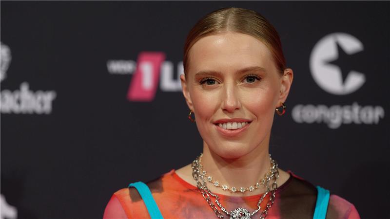 Blonde Frau mit Statement-Kette und Dutt.