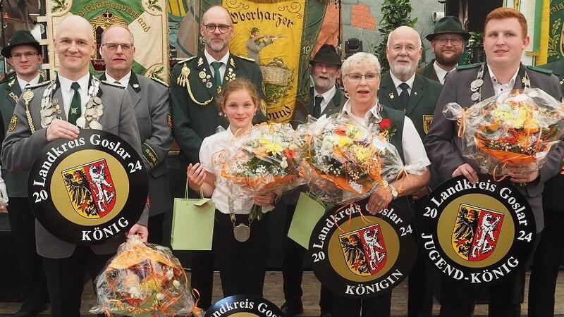 Landkreiskönige 2024 proklamiert Die Landkreiskönige im Überblick (v.l.) König Alexander Just, Landkreislichtkönigin Thomke Anna Luise Spahn, Landkreiskönigin Dagmar Graf, Landkreisjugendkönig Benedict Klohr. Im Hintergrund zu sehen sind die Vorsitzenden und Fahnenträger der Kreisschützenverbände Goslar, Oberharz und Bad Gandersheim.