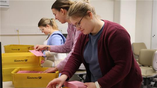 Die Landkreismitarbeiterinnen Nadine von Cisewski (hinten), Jana Zoellner (Mitte) und Sabrina Kay aus dem Wahlbüro des Landkreises sortieren die bislang eingegangenen Briefwahl-Unterlagen den jeweiligen Bezirken zu.