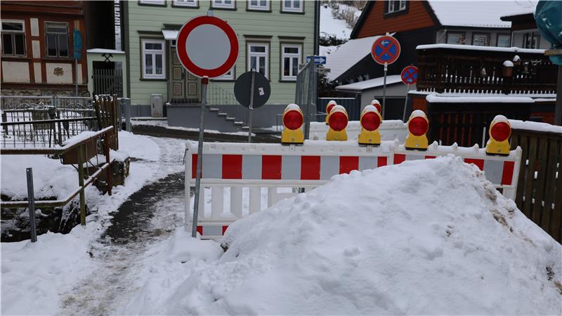 Eine teilweise gesperrte Brücke vor der ein Haufen Schnee liegt
