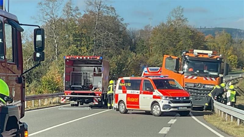 Das Foto zeigt einen Lastwagen und mehrere Rettungs- und Feuerwehrwagen mitten auf einer Straße.