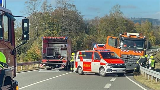 Das Foto zeigt einen Lastwagen und mehrere Rettungs- und Feuerwehrwagen mitten auf einer Straße.