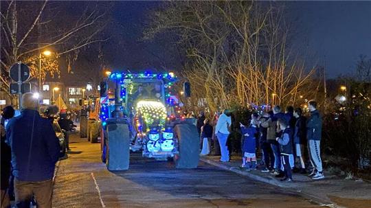 Viele Menschen stehen am Straßenrand und erfreuen sich an der Lichterfahrt der Traktoren.