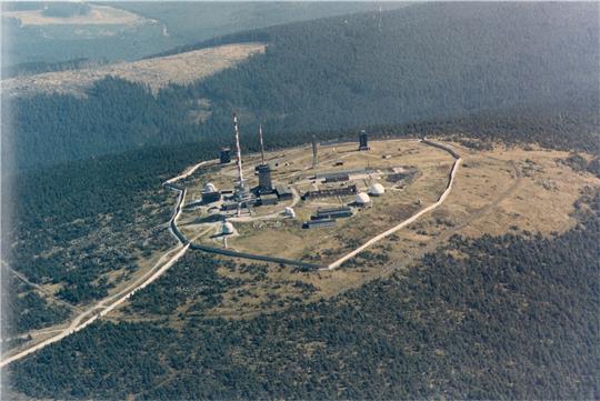 Die Luftaufnahme entstand aus einem Hubschrauber des Bundesgrenzschutzes und zeigt das Brockenplateau Ende der 1980er Jahre. Wie Pilze scheinen die Radome aus dem Boden zu schießen – die Kuppeln beherbergen die Spionagetechnik. Umfasst ist die Kuppe von einer Mauer. Foto: BGS-Archiv/Heimatmuseum Abbenrode