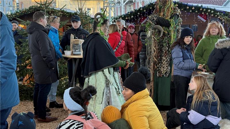 Kinder lauschen auf einem Markt einer Märchenerzählerin.