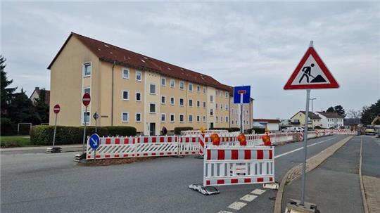Straßensperrung mit Absperrungen und Verkehrsschildern vor einem mehrstöckigen Wohnhaus in einer Wohnstraße.