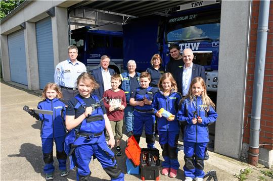 Die „Minis“ von Bettina Zellmer (hinten, 3.v.re.) wollen richtig mitmischen beim THW. Die Spende des Lions-Clubs, die Thomas Brych (hinten rechts) und Michael Schilling (hinten, 2.v.li.) mitbringen, kommt da gerade zur richtigen Zeit.  Foto: Kempfer