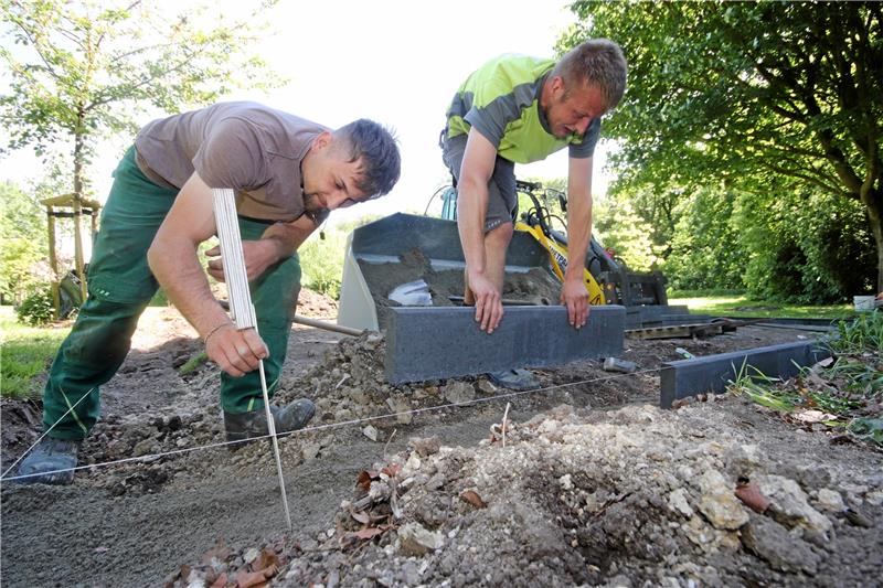 Liebenburg bekommt einen Fitnesspark unter freiem Himmel Die Mitarbeiter der beauftragten Garten- und Landschaftsbaufirma setzen die Randkantensteine, die das Areal begrenzen, auf denen sie die Geräte errichten. Foto: Gereke