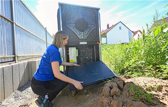 Die Mitarbeiterin eines Heizungsbaubetriebs inspiziert vor einem neu gebauten Wohngebäude eine Wärmepumpe.  Foto: dpa