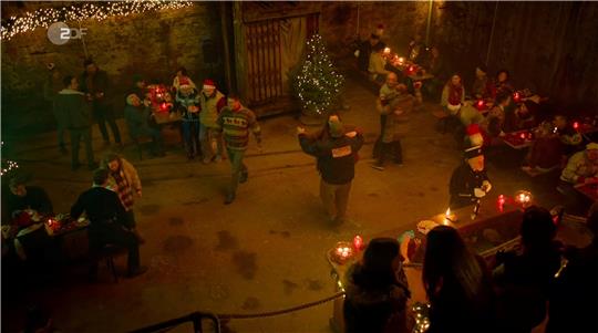 Die Mitglieder des CTC Bad Harzburg – hier links mit Zipfelmütze das Ehepaar Seidel und rechts ohne Mütze Jürgen Vogelbein – und Michael Dallibor als Bergmann vorn an der Bar wirken im ZDF-Weihnachtsfilm mit. Screenshots: GZ/Quelle: ZDF-Mediathek