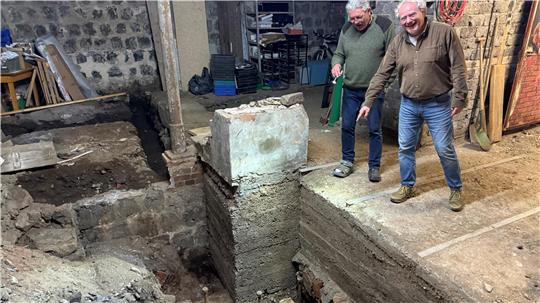 Die Museumsleiter Hans-Günter Schärf (links) und Christian Barsch zeigen auf die Stelle unter der Erde im Keller des Bergwerksmuseums, in der das Sägewerk gestanden hat.