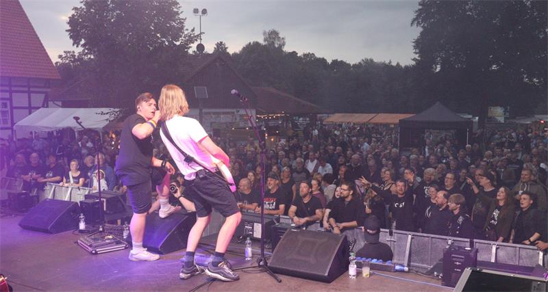 Zwei Musiker auf einer Bühne, dahinter eine Menschenmasse.