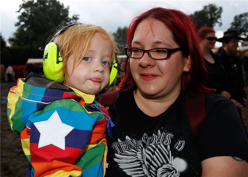 Direkt auf die Ohren: Wie schütze ich mein Gehör auf Festivals? Die Mutter schützt die Ohren ihres Kindes auf einem Wacken Open-Air-Festival. Foto: dpa