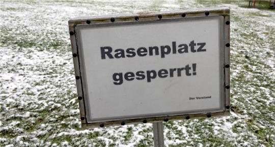 Auf einem verschneiten Fußballplatz steht ein Schild mit der Aufschrift Rasenplatz gesperrt.