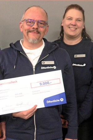 Zwei Personen präsentieren einen symbolischen Scheck.