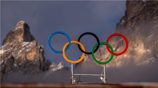 Die Olympischen Ringe auf dem Dach der Curling Halle sind vor den Bergen in Cortina zu sehen. Die Olympischen Winterspiele 2026 finden in Mailand und Cortina d’Ampezzo statt.
