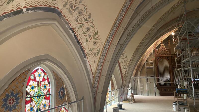 In die Bad Harzburger Lutherkirche kehrt das Licht zurück Die Ornamentbögen über den Fenstern an der Südwand sind beinahe komplett wieder retuschiert, unterhalb der Gerüstplattform ist auch die restliche Wand bereits von der Dispersionsfarbe befreit.