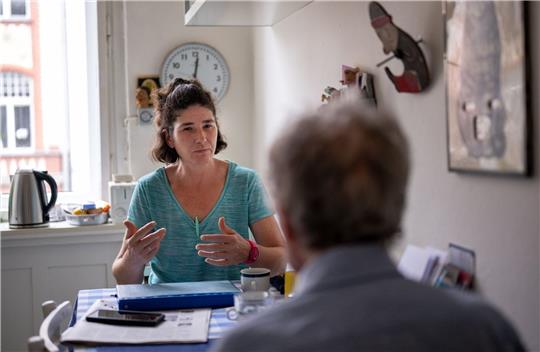 Die Pflegerin Ramona Rössner spricht beim Hausbesuch mit ihrem pflegebedürftigen Patienten Andreas Seltzer.
