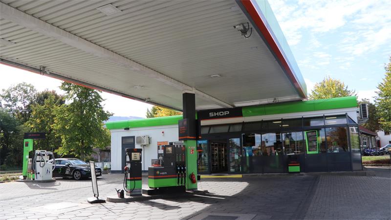 Tankstelle mit Shop, Zapfsäulen und einem schwarzen Auto auf dem Gelände.